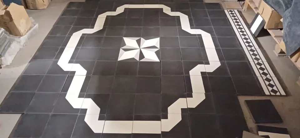 Black and white floor tiles laid out with a central star and stepped white border